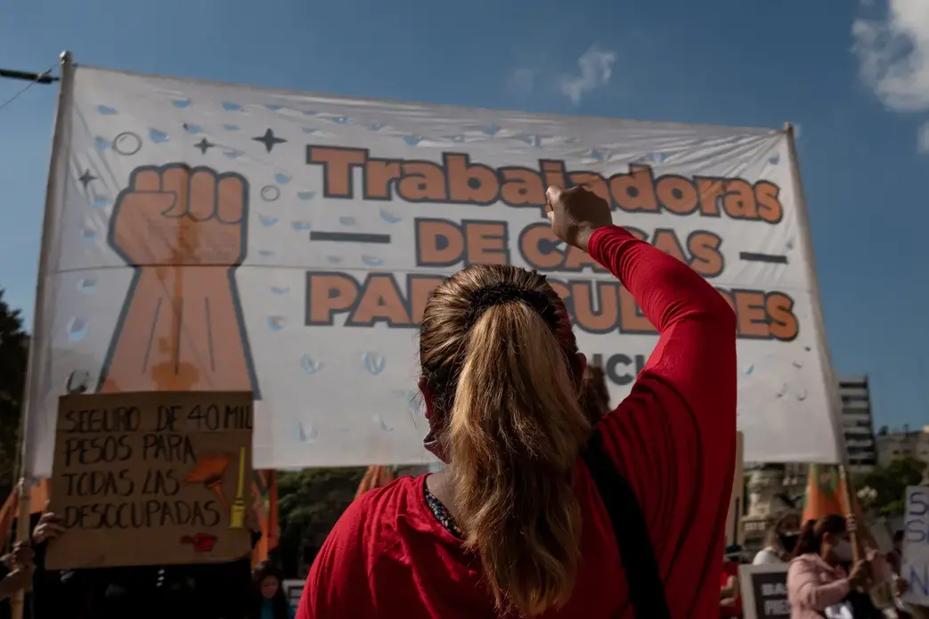 A person stands, with their arm raised and back to the camera, in front of a banner.