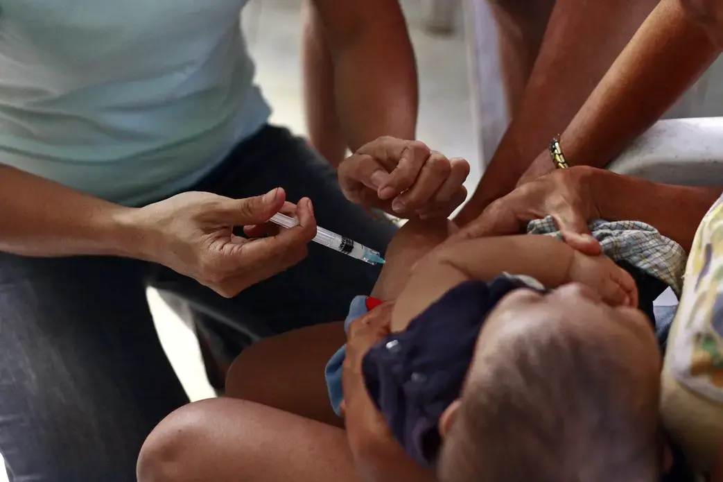 Health worker injecting vaccine to child.