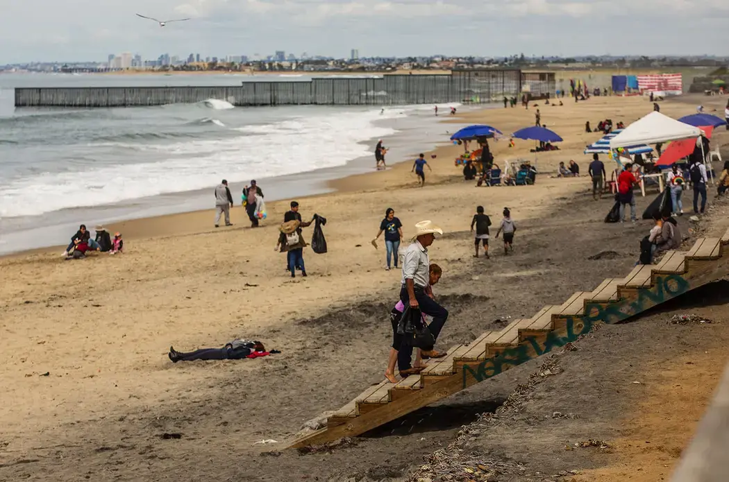 Daysi works ironing clothes at a laundry in Tijuana and her son, Jimmy, 12, sells shrimp at the beach near the U.S. border. Image by Erika Schultz. Mexico, 2019.