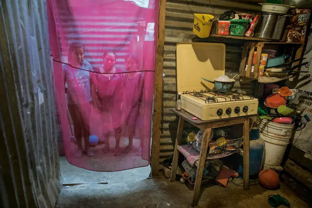 A month's worth of propane for the small gas stove costs Rosa Vicente Garcia (flanked here by her two daughters) and her husband more than two days' work at the Guatemala City landfill, where they scavenge for plastic and metal. Image by Lynn Johnson. Guatemala, 2017.