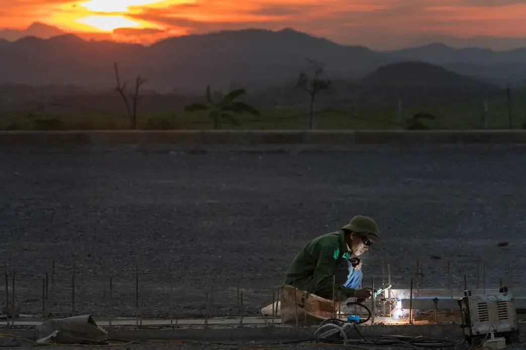 A welder works on a much-needed additional warehouse for nutrients that are added to animal feed at TH Milk's operations in Nghia Son, Vietnam. Image by Mark Hoffman. Vietnam, 2019. 