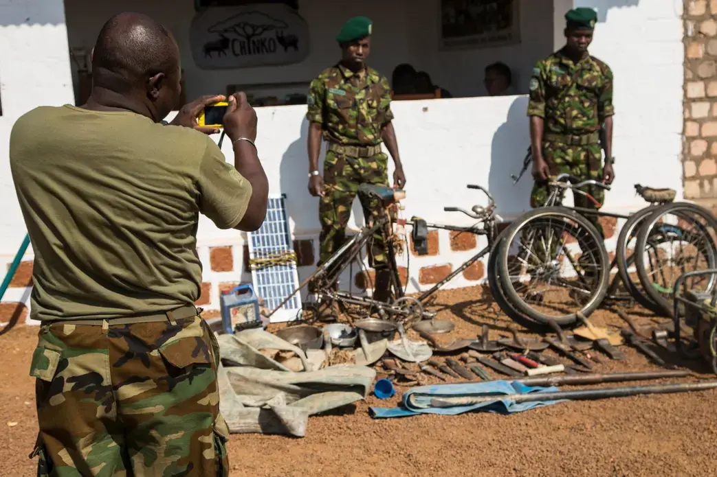 Two rangers pose for a photo next to machetes, knives, spades and other equipment which have been confiscated from poachers and laid out at Chinko’s HQ. Image by Jack Losh. Central African Republic, 2018.