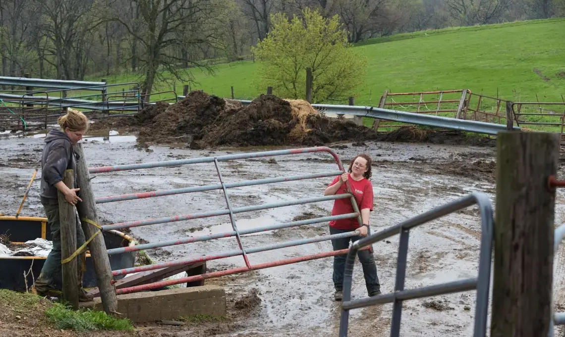 Emily, left, and Brandi Harris move a gate on their organic dairy farm. Image by Mark Hoffman. United States, 2019.