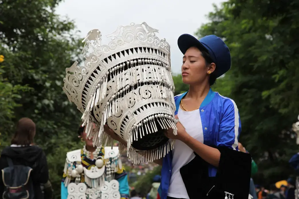 A beauty contest participant sits beside her silver headdress during Torch Festival celebrations in Liangshan prefecture, Sichuan province. Image by Max Duncan. China, 2016.