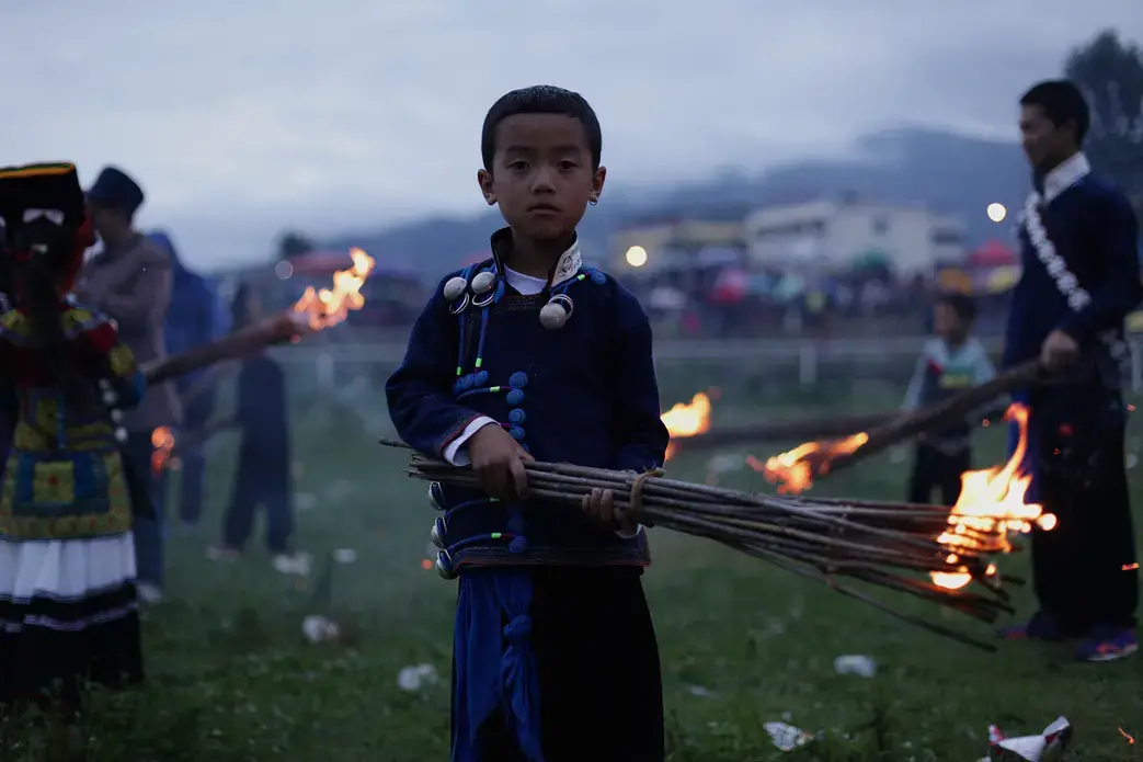 An Yi boy holds a flaming torch during Torch Festival celebrations in Liangshan Prefecture, Sichuan province. Image by Max Duncan. China, 2016.