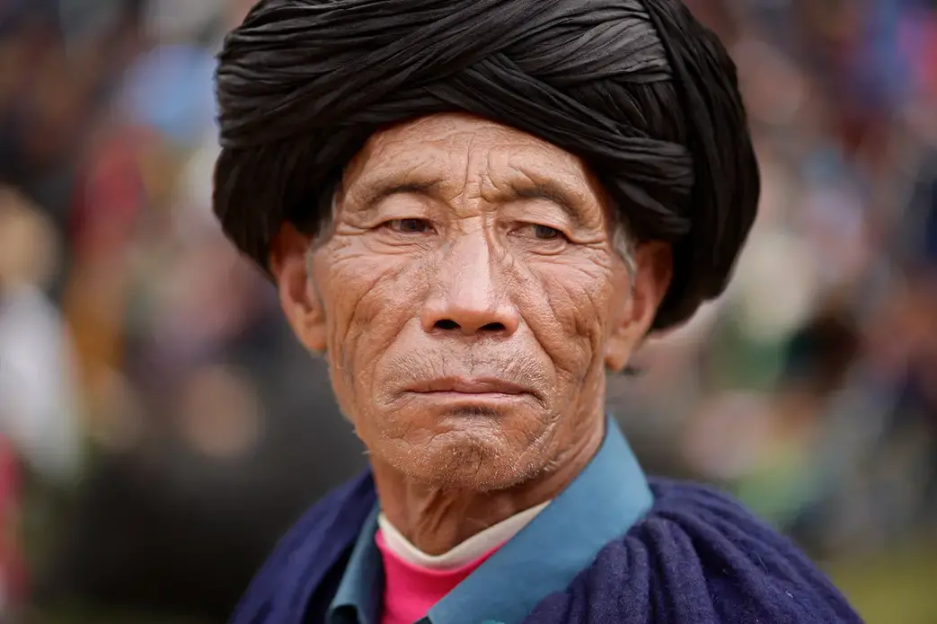 A Yi man joins crowds for performances during Torch Festival celebrations in Liangshan prefecture, Sichuan province. Image by Max Duncan. China, 2016.