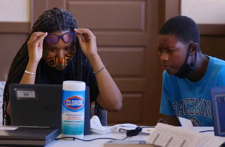 On the first day of school Ty’reese Johnson, a freshman at Myers Park, works through his computer challenges with Tijua Robinson, director of the Grier Heights Community Center. Johnson, who lives in the Grier Heights neighborhood of Charlotte, doesn’t have wifi at home and relies on the Grier Heights Community Center for internet access. Image by Jessica Koscielniak. United States, 2020.