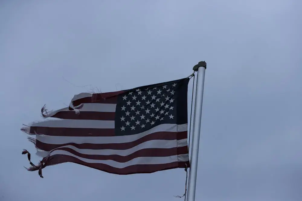 A tattered U.S. flag whips in a heavy wind on Sunday, April 19, 2020, in Dawson, Ga. Image by Brynn Anderson / AP Photo. United States, 2020.
