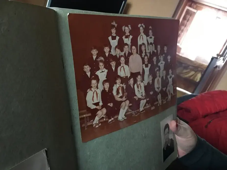 Anna Kireeva shows one of her class photos from the Soviet era Murmansk. Image by Amy Martin. Russia, 2018.