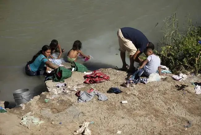 Migrants swim and wash clothes in the Rio Grande under the Gateway International Bridge in Matamoros. Image by Miguel Gutierrez Jr. Mexico, 2019.