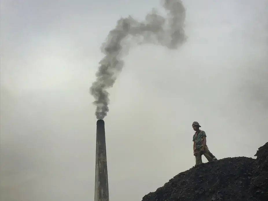 Massive piles of coal are frequent playgrounds for young Dhaka residents. Cleaner-burning and more efficient kiln designs have been developed, but the economic realities of conversion have slowed industry reform here. Image by Larry C. Price. Bangladesh, 2018.
