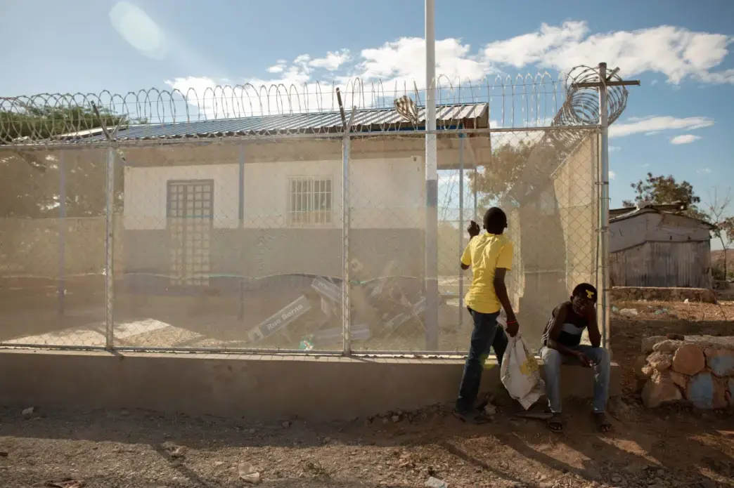 Boys rest along the foundation of an inaugurated but not yet staffed police post in the Canaan 1 neighborhood. Currently there are just 14 police officers stationed in Canaan, serving the city’s 280,000 to 320,000 residents. Image by Allison Shelley. Haiti, 2019.