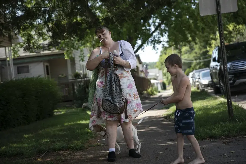 Brittany Cunningham 31, walks down the street with her nephew and his dog in Nelsonville, Ohio. Image by Wong Maye-E/AP Photo. United States, 2020.