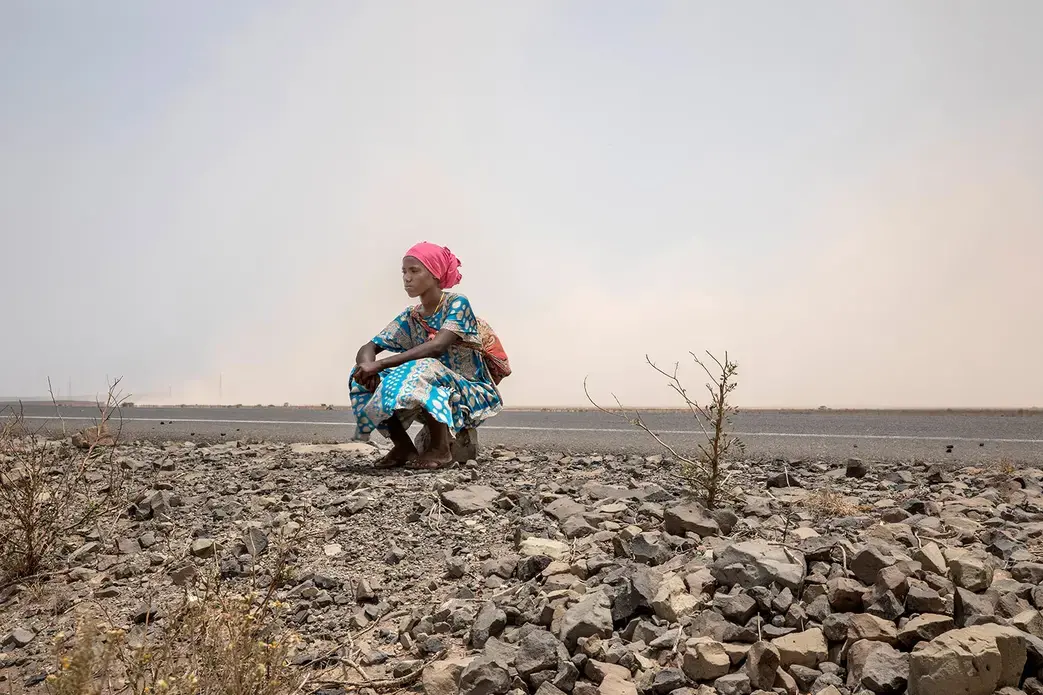In this July 12, 2019 photo, 18-year-old Raheema Sanu, an Ethiopian migrant, rests on the side of a road, about 31 miles (50 kilometers) from Ali Sabeih, Djibouti. Image by Nariman El-Mofty / AP Photo. Djibouti, 2019.