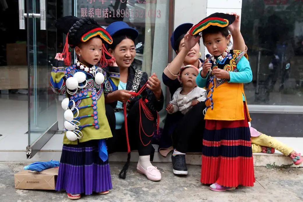 Yi children put on traditional dress during Torch Festival celebrations in Liangshan prefecture, Sichuan province. Image by Max Duncan. China, 2016.
