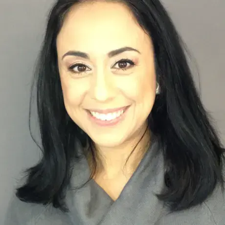 A woman wearing a grey shirt smiles at the camera.