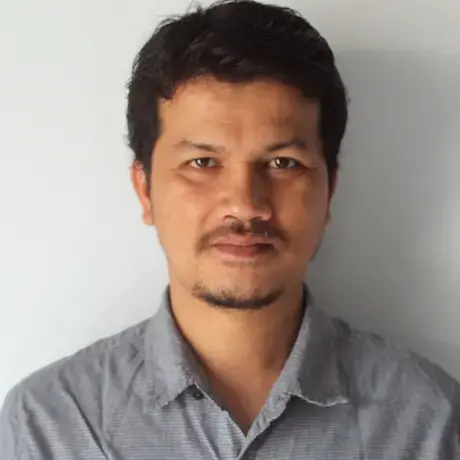 Tonggo_Simangunsong_-_foto.jpeg A person wears a grey shirt and has short black hair.