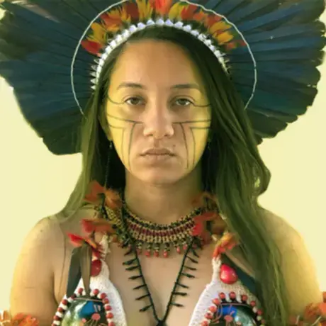 Samela Satere Mawe.png A person with black hair and Indigenous headdress looks into the camera.