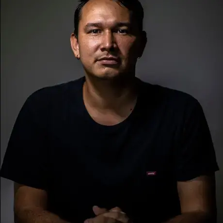 A man with dark hair looks into the camera