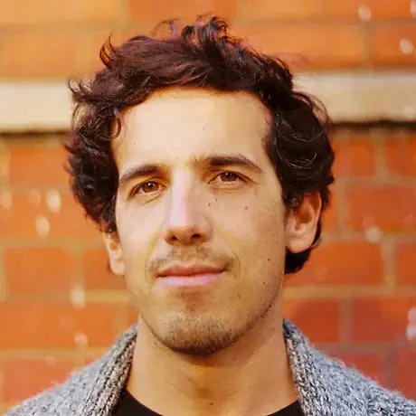 A person has curly brown hair and wears a grey jacket.