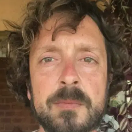 Screen Shot 2022-05-06 at 6.08.19 PM.png A man wears a white shirt and has brown curly hair.