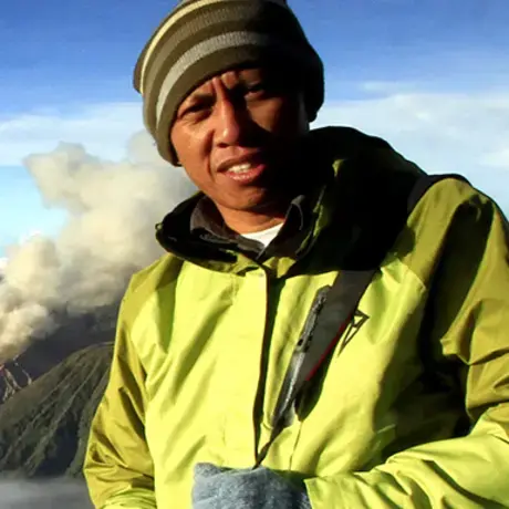 FOTO-RONNY-BUOL.jpg A man wearing a beanie and a yellow jacket. In the background, there is a mountain range and fog.