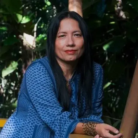 A woman wears a blue-striped shirt with a bracelet. She has black hair and looks at the camera.
