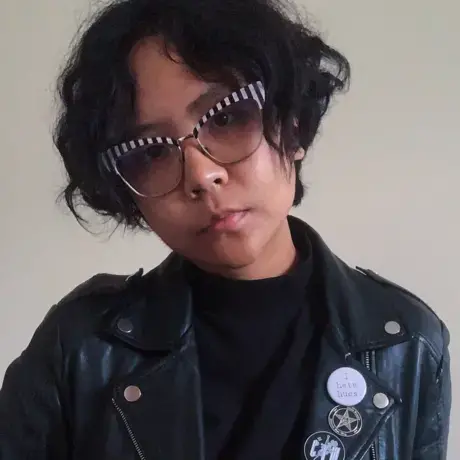 Fieni-Aprilia-e1624634148642.png a woman with large glasses stares into the camera