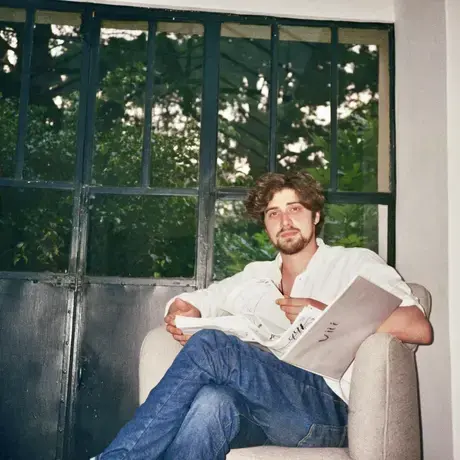 A man sits in a chair reading a book