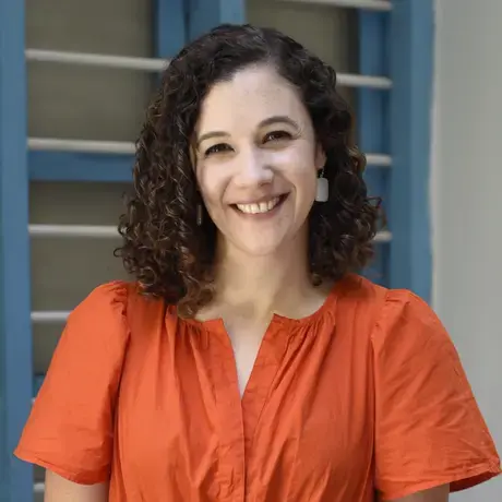 A woman in a bright orange dress with curly hair.