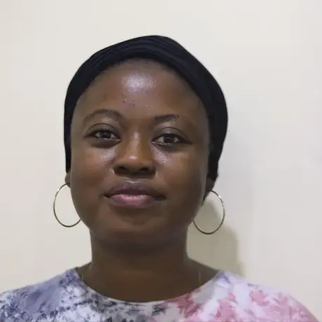 A woman with dark skin and dark hair wearing hoop earrings and red and blue shirt.