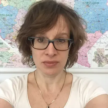 A woman with glasses and short hair wearing a white tshirt