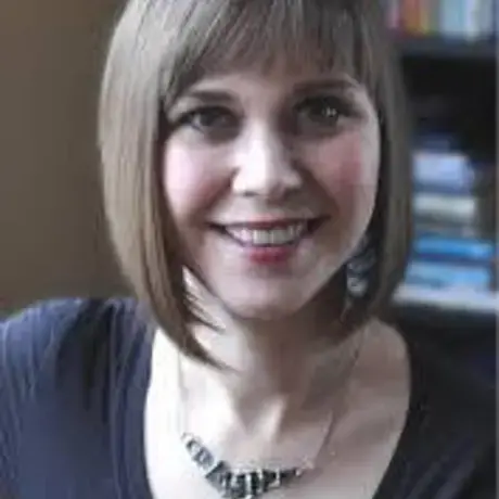 A woman with a short blonde bob with bangs wearing a dark t-shirt