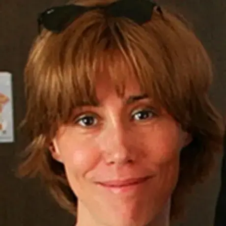 A woman with short red hair and bangs wearing sunglasses on her head