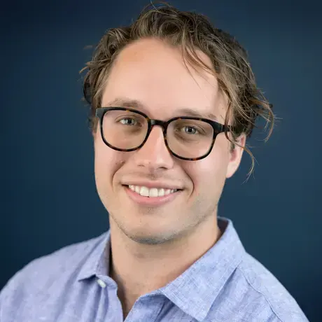 Headshot of James wearing glasses and a light blue collared shirt