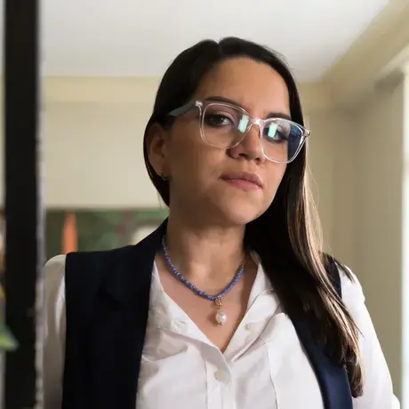Thalíe Ponce wears glasses and a white button down shirt