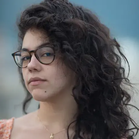 Headshot of Camille wearing glasses and an orange shirt