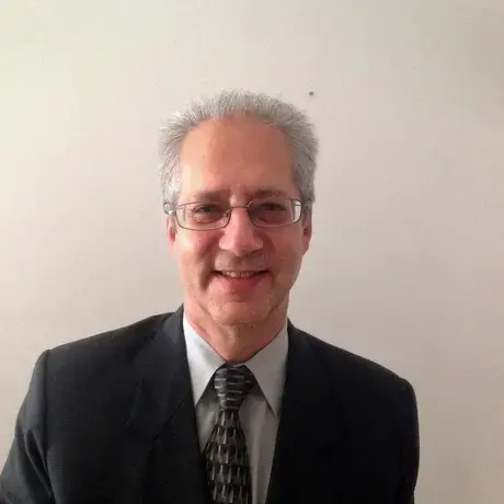 Headshot of Mac wearing a suit and tie against a white background