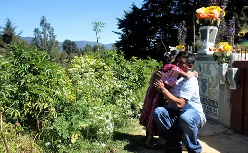 Gilberto Gomez-Gonzales hugs his youngest daughter during a visit to the cemetery where his eldest daughter, Claudia Gomez-Gonzalez, was laid to rest after she was killed by a U.S. Border Patrol agent in May and repatriated to her hometown of San Juan, Quetzaltenango, Guatemala. Image by Kristian Hernandez. Guatemala, 2018.