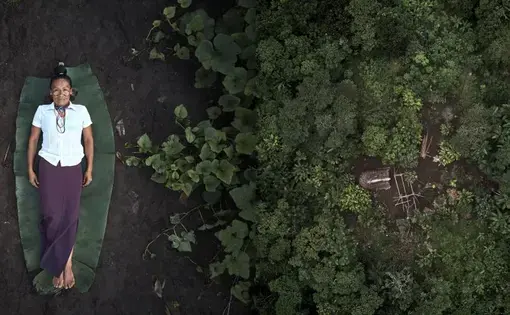 Verónica é uma indígena achuar que trabalha como parteira em uma cultura em que, segundo ela, as mulheres têm vergonha de dar à luz. À esquerda, Verónica deitada no chão. À direita, o jardim de plantas medicinais, onde ele cultiva plantas ancestrais para tratar seus pacientes. Imagem de Pablo Albarenga. Equador, 2019.