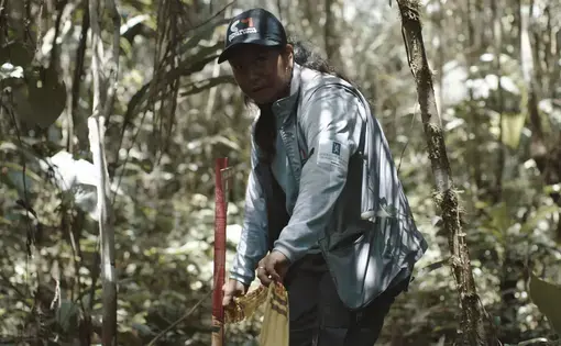 Siona leader Adiela Mera Paz tapes off an area suspected of landmine contamination as part of her work for The Colombian Campaign Against Landmines in Siona territory in December 2019. A still from the New Yorker film “SIONA: Amazon’s Defender’s Under Threat.” Image by Tom Laffay. Colombia, 2019.