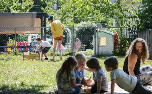 Bell's School teacher Jodie Williams helps Oliver Fink, 5, spray rabbit repellent on vegetables growing in a raised bed garden as other children play on a blanket in the shade at the preschool in Fletcher on June 22, 2020. Image by Angeli Wright/Asheville Citizen Times/North Carolina News Collaborative. United States, 2020.
