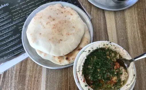 Hummus, pictured here, is more than just a snack. It's considered "worker's food." Historically, it was used to feed those with manual labor jobs who needed a filling breakfast that would get them through an exhausting work day. Today, many hummus establishments continue to exclusively serve the blended mix of tahini, chickpea, olive oil and lemon juice—opening early in the morning and closing once they run out. Image by Carly Graf. East Jerusalem, 2019.