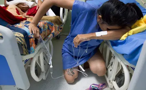 Venezuelan migrant Yulianis Rodriguez, hunches down in Maicao, Colombia's Hospital San Jose as she struggles to cope with the pain of labor without an epidural on May 5, 2019. She crossed into Colombia alone to give birth to her baby son who was born 'stateless' and is now among 24,000 children who were granted Colombian citizenship by the country's government. Image by Megan Janetsky. Colombia, 2019.