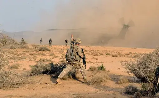 U.S. Army Sergeant Kevin Fischer, Sight Security Team 1st Battalion 161st Field Artillery, signals his security team to fill in the security perimeter, August 22, in the deserts of Djibouti. Image courtesy of the U.S. military's press photos. Djibouti, 2011.