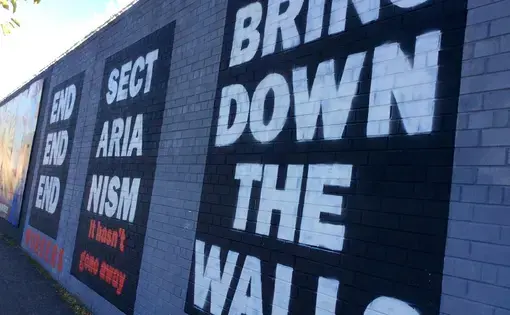 A mural reading 'End Sectarianism: Bring Down The Walls' on the Falls Road mural wall in Belfast. Image by Julia Canney. Northern Ireland, 2018.