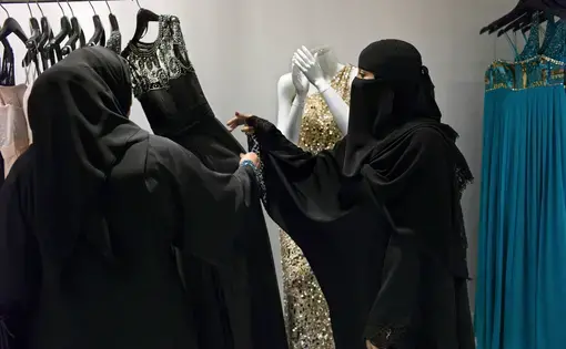 A Saudi employee helps a customer at a dress shop in Al Faisaliah Mall. Image by Kate Brooks. Saudi Arabia, 2013.