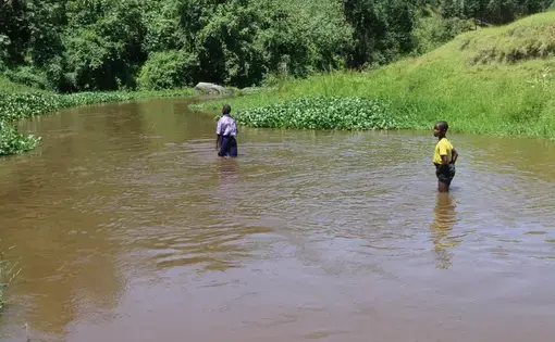 Two children standing in the Rwizi River