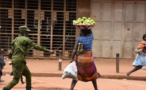A LDU soldier raising a cane to beat a woman in Kampala, Uganda in March, 2020.
