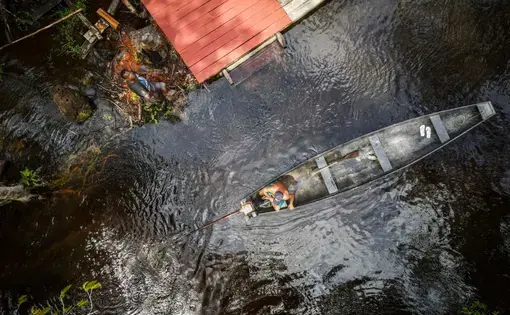 Vista aérea de um barco num rio e de um cais.